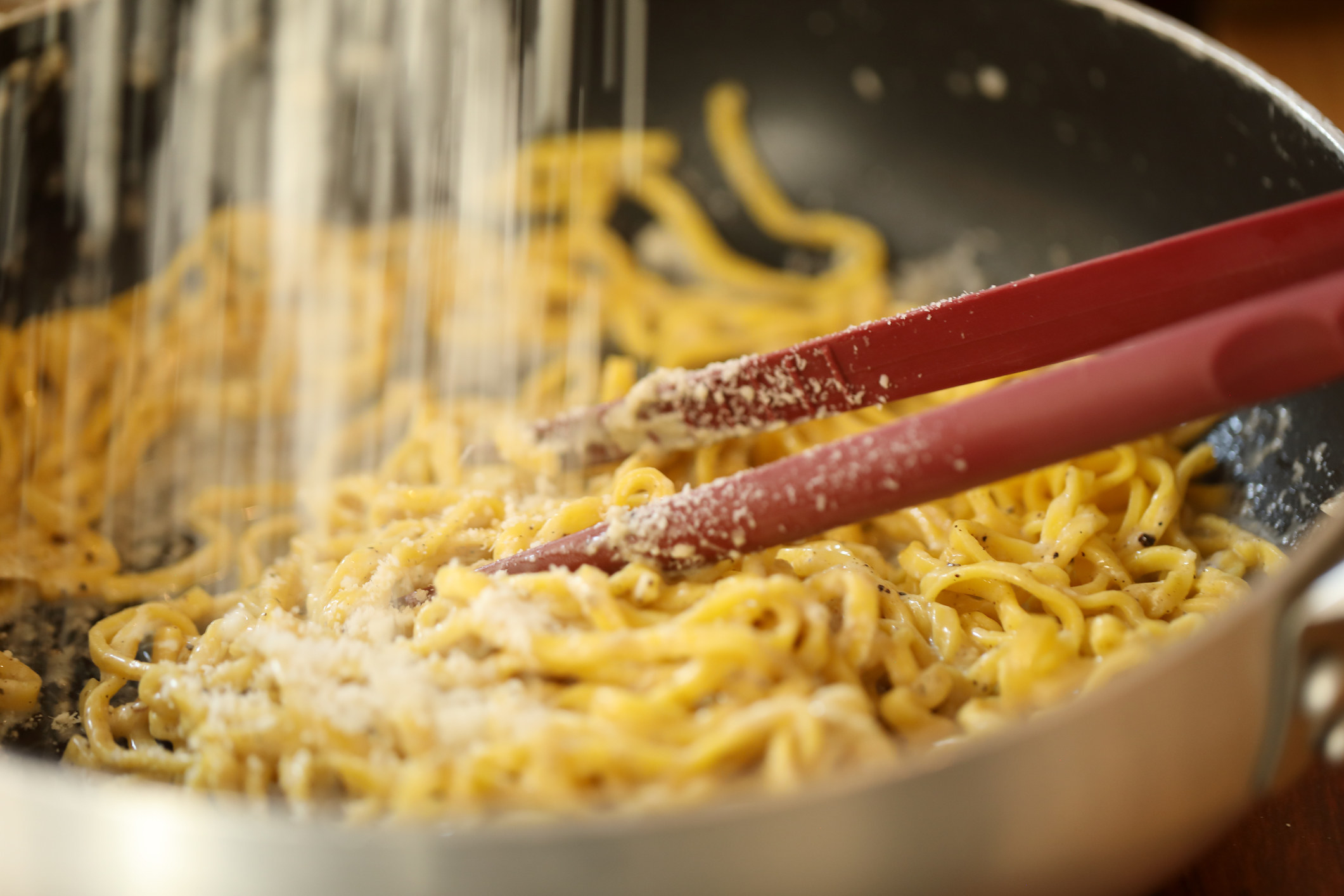 Adding cheese to skillet of pasta