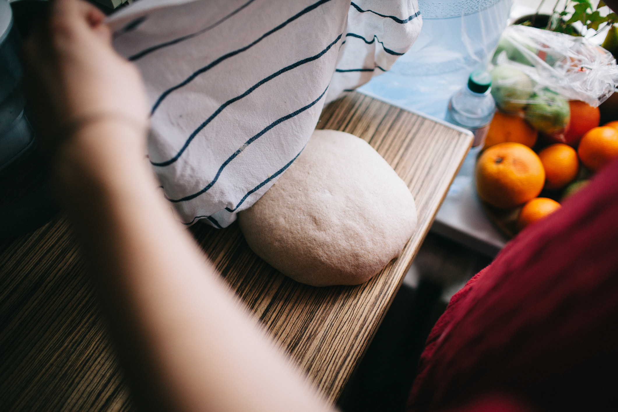 Holding towel above a piece of bread dough