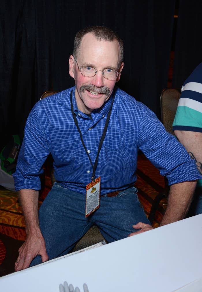 Smiling man in glasses and jeans sitting down