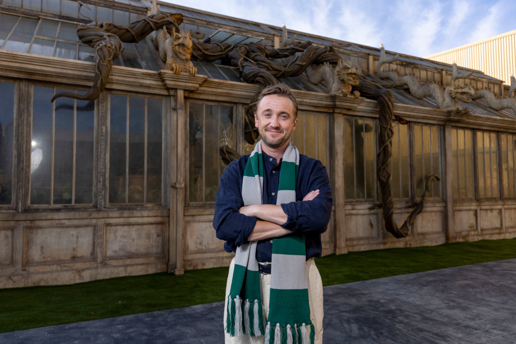 Tom, with his arms crossed, proudly wearing a Slytherin scarf around his neck