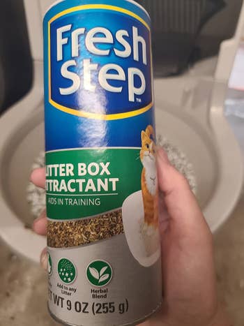 reviewer holding the container of litter box attractant