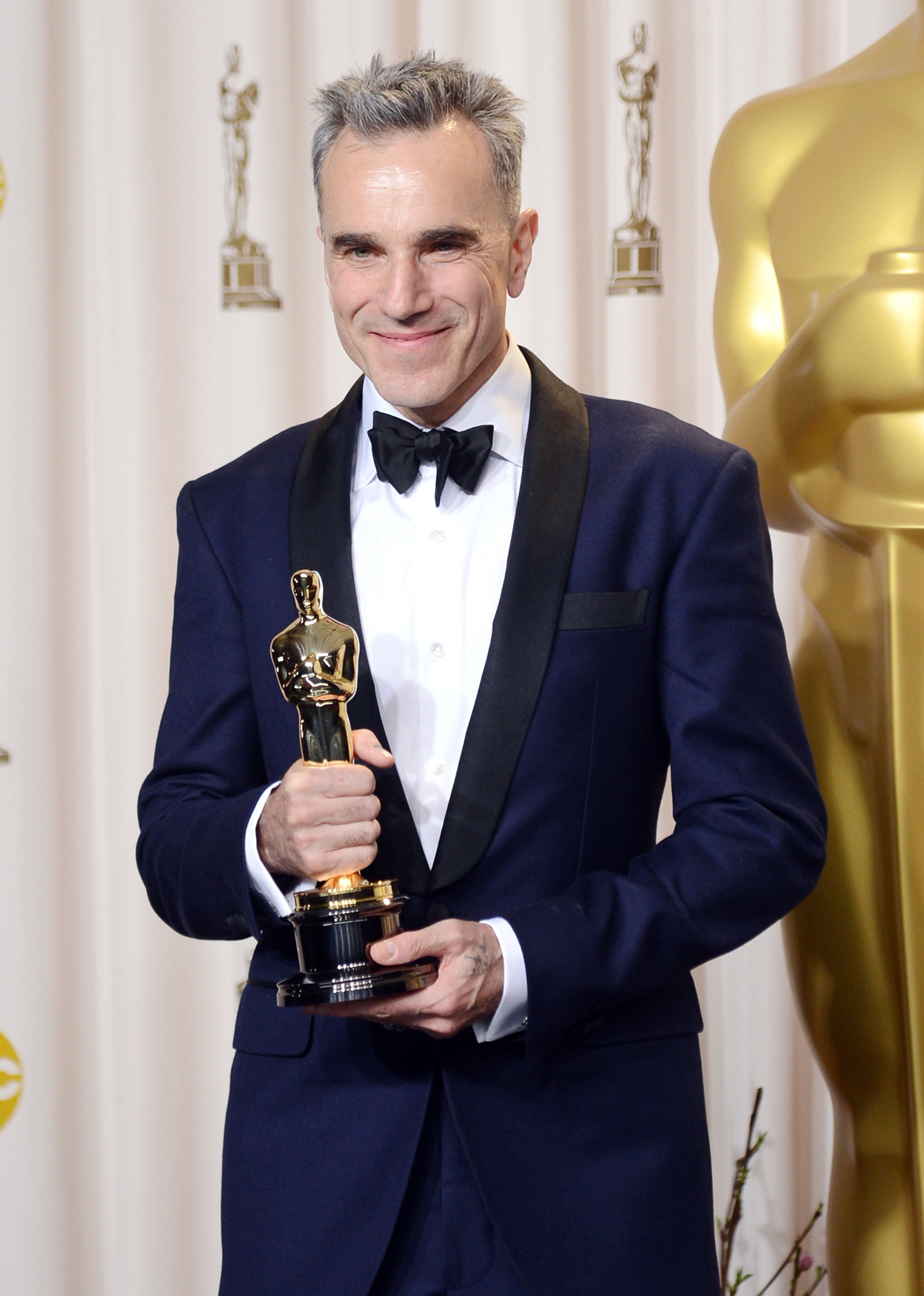 Smiling Daniel wearing a suit and bow tie and holding an Oscar