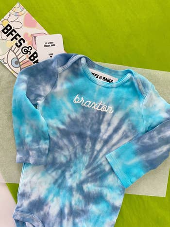 a blue tie dyed long sleeve body suit that says 