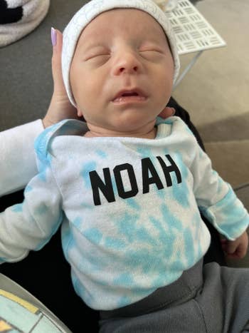 editor's baby in a blue and white tie dye longe sleeve that says noah on it