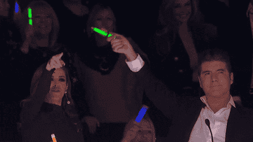 Simon Cowell waving a glow stick in the air in &quot;The X-Factor&quot;