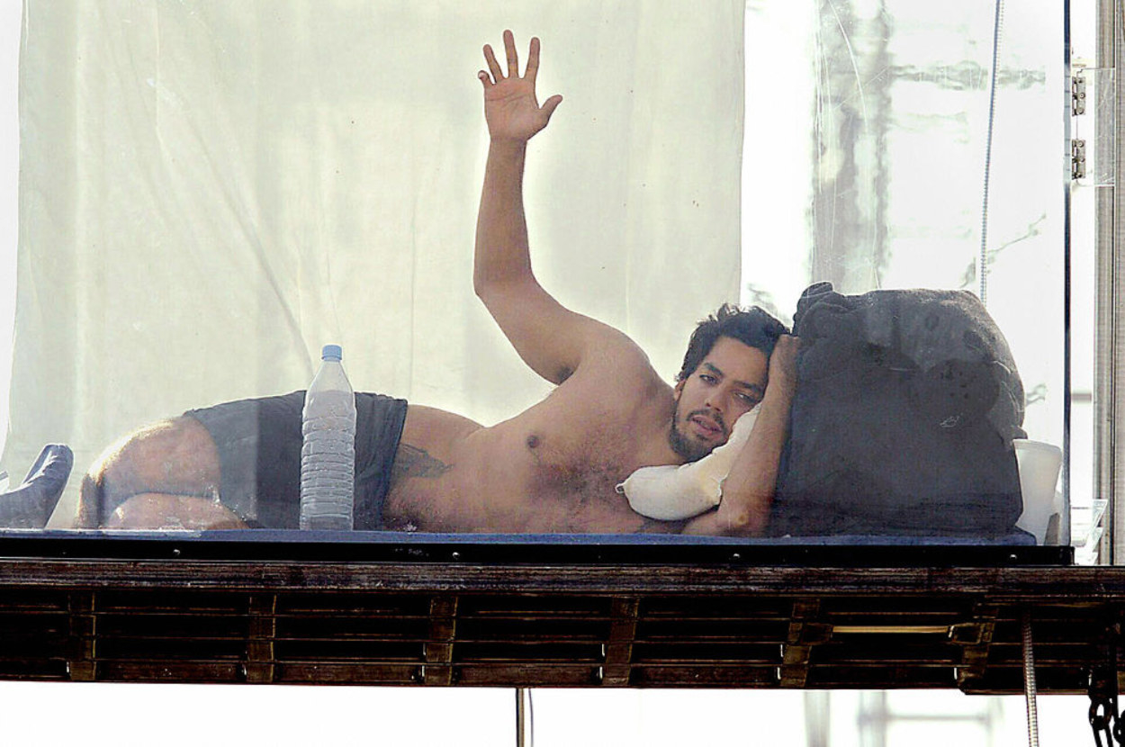 david blaine resting with a bottle of water in his box