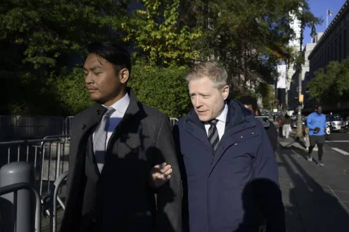 Anthony Rapp and his partner Ken Ithiphol in formal clothing walk arm in arm outside a courthouse