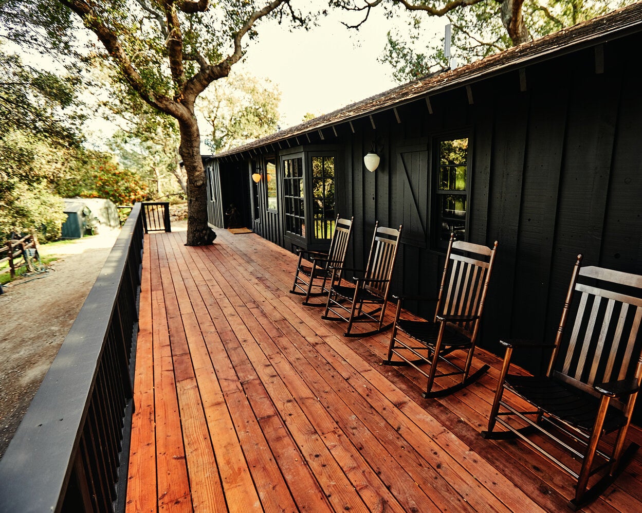 cedar deck with four rocking chairs against the all black house