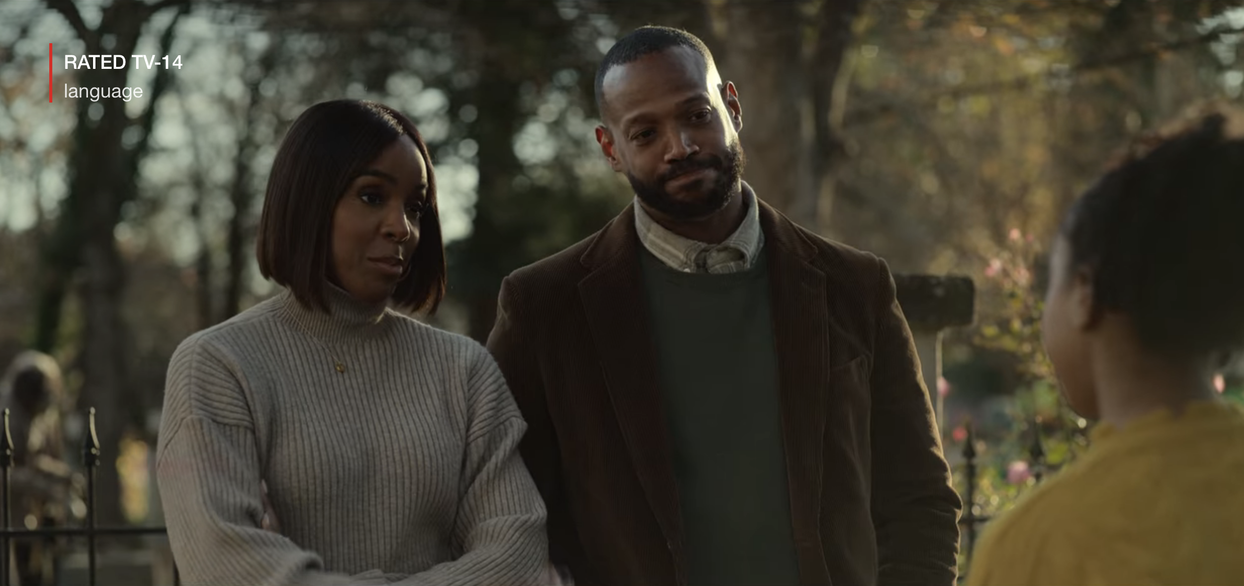 Kelly and Marlon standing side-by-side as they speak to someone outside in a scene from The Curse of Bridge Hollow