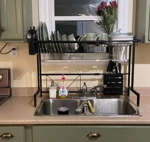 a reviewer photo of the over-the-sink dish rack full of dishes
