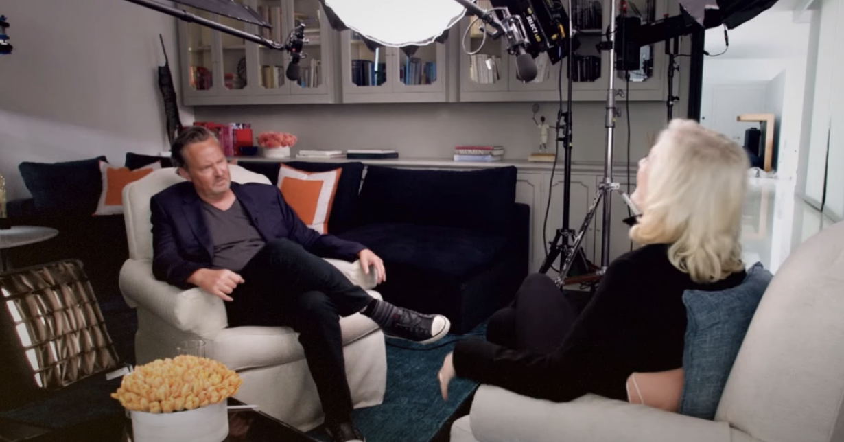 matthew sitting in a chair across from Diane under lights for the interview