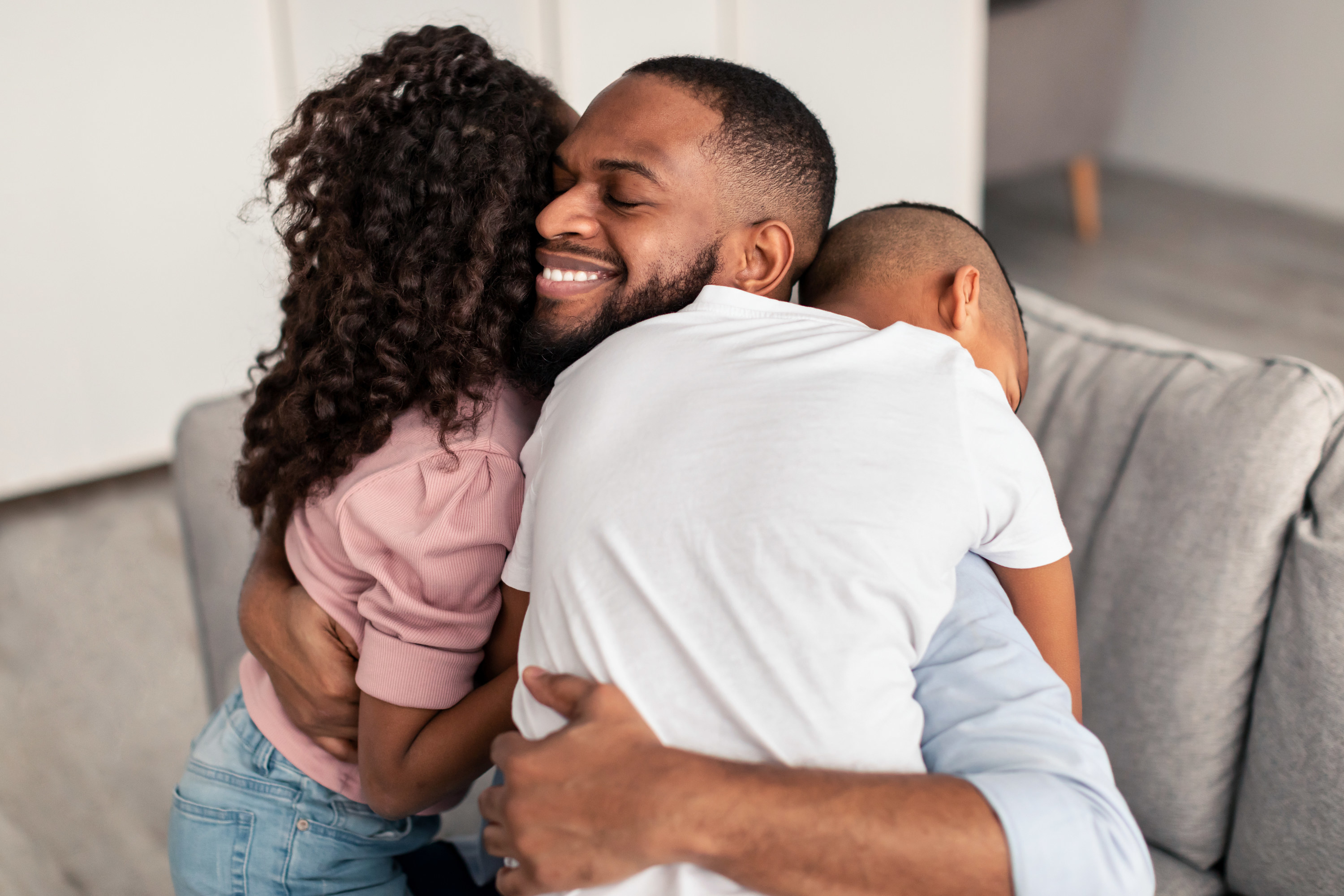 Happy Loving Family. Portrait of cheerful smiling African American dad embracing his little children, expressing love. Girl, boy and man hugging, enjoying time together, celebrating Father&#x27;s day