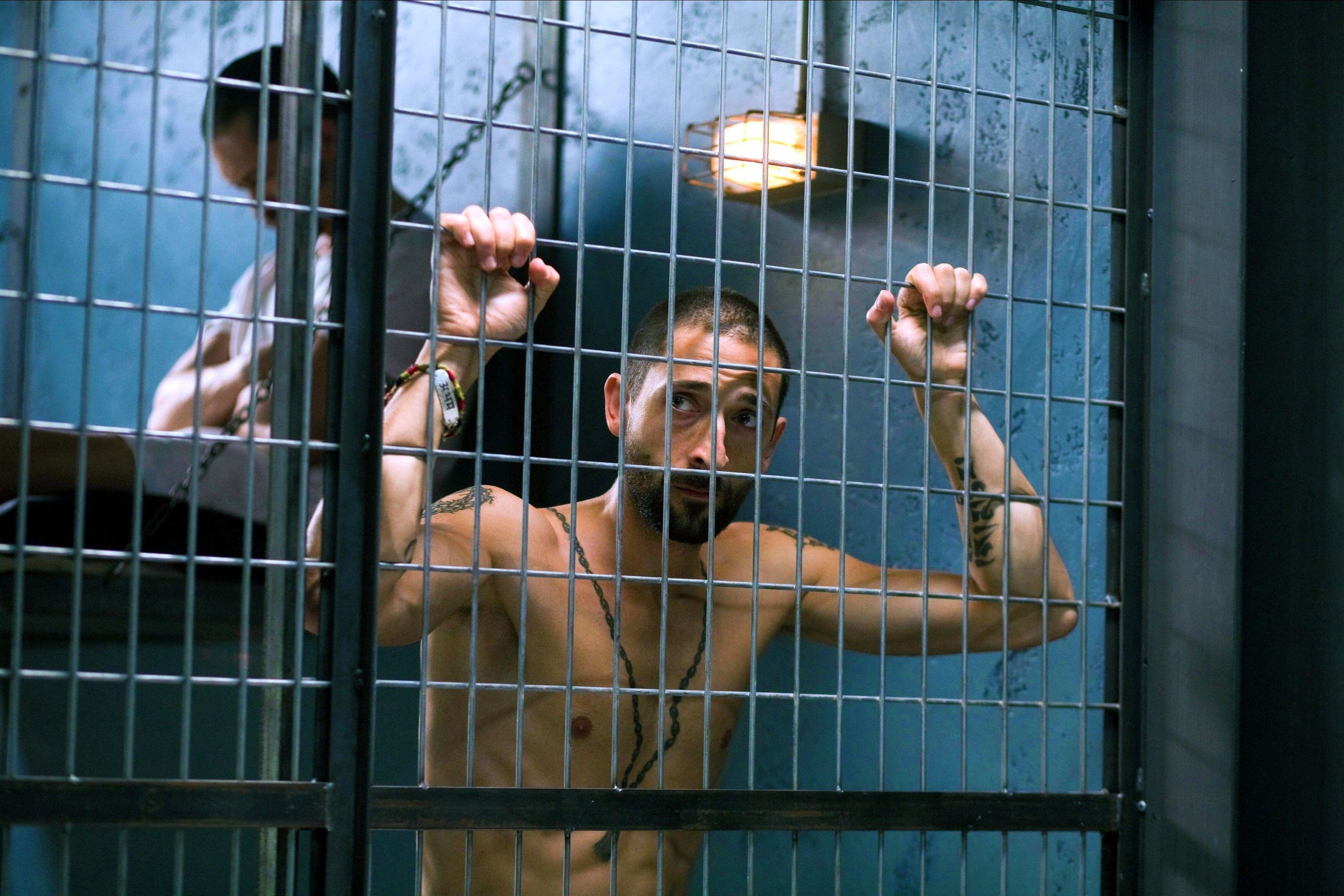 A gaunt man stands inside of a makeshift prison cell