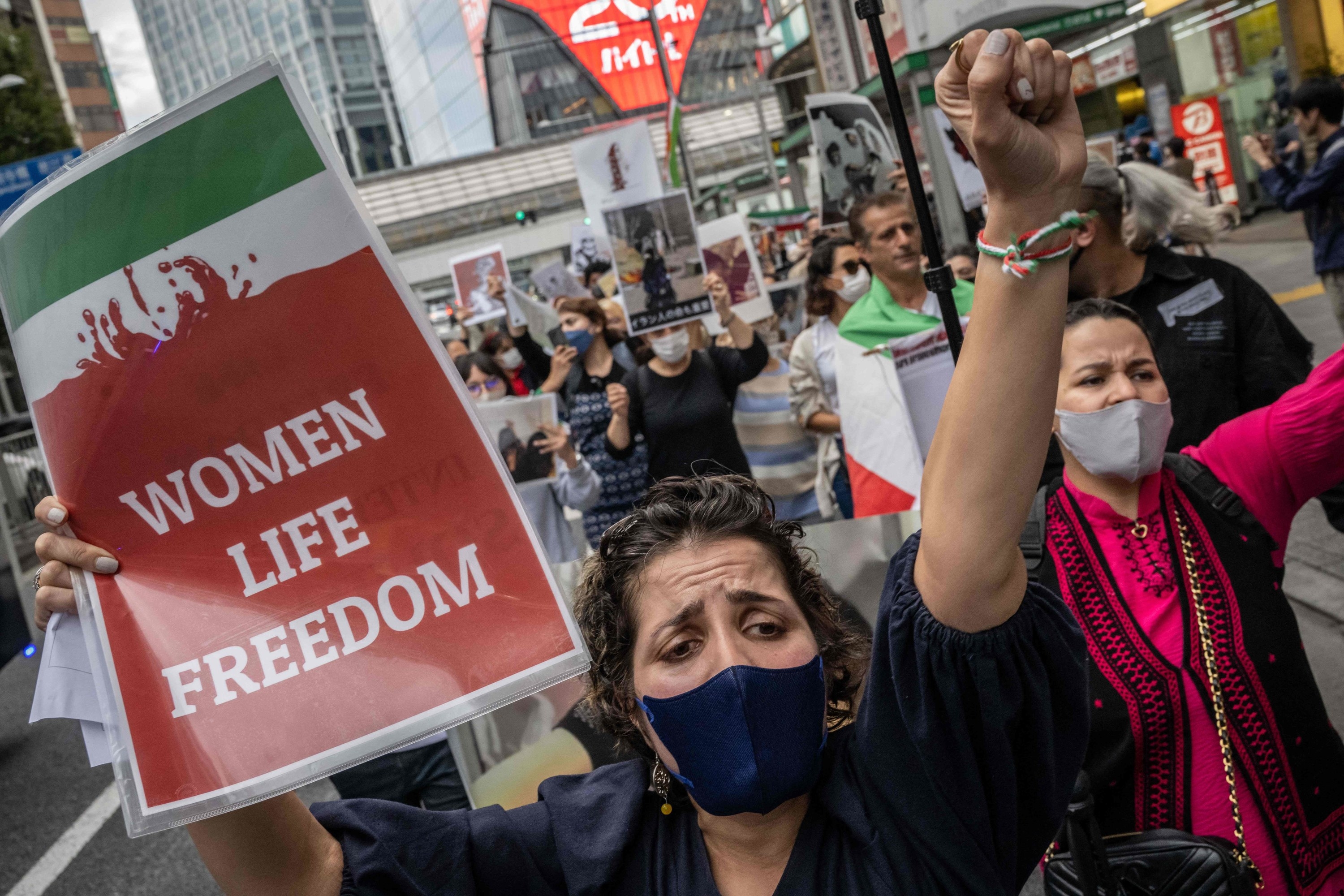 A protestor holds a sign reading &quot;women, life, freedom.&quot;