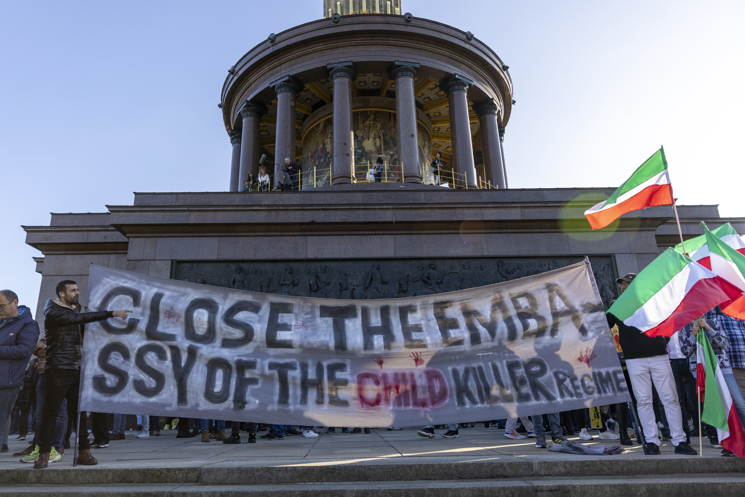 Protestors stand outside Berlin&#x27;s Iran embassy with the sign &quot;close the embassy of the child killer regime.&quot;