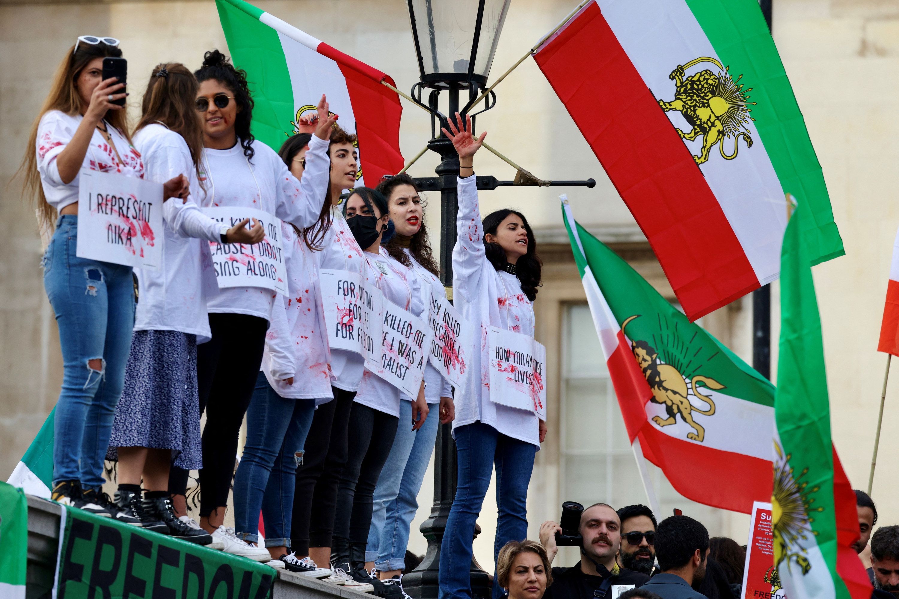 Protestors stand on an elevated surface.