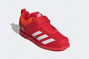 Red Adidas shoes with three white stripes and a strap that covers the laces
