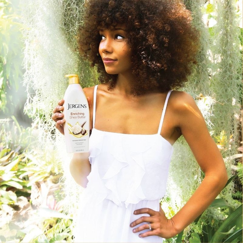 A person with an afro holding a bottle of lotion