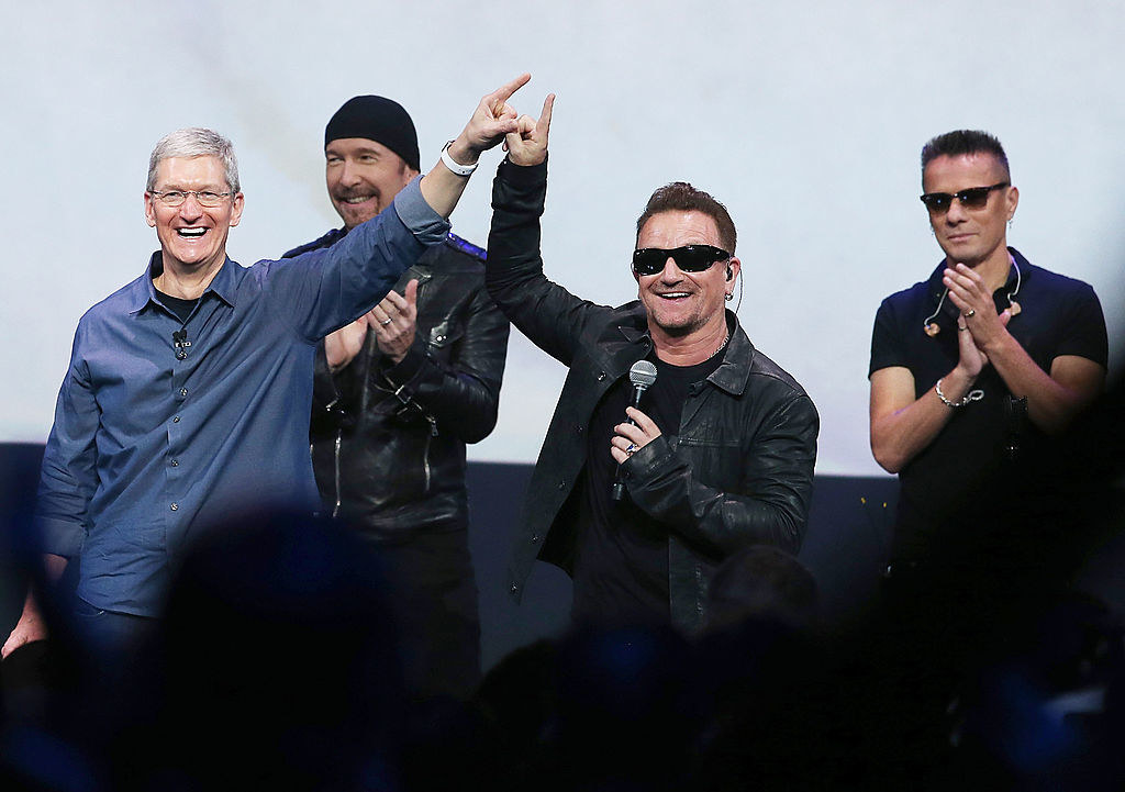 Tim Cook onstage with U2 as he and Bono hold up their hands together