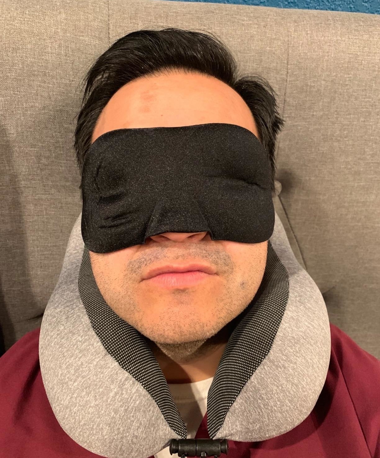 Reviewer sleeping with pillow adjusted around neck and black eye mask over eyes