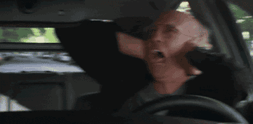 Larry David holding his ears while driving.