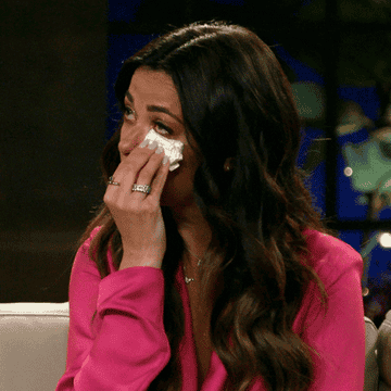 a woman crying and dabbing away her tears with a tissue