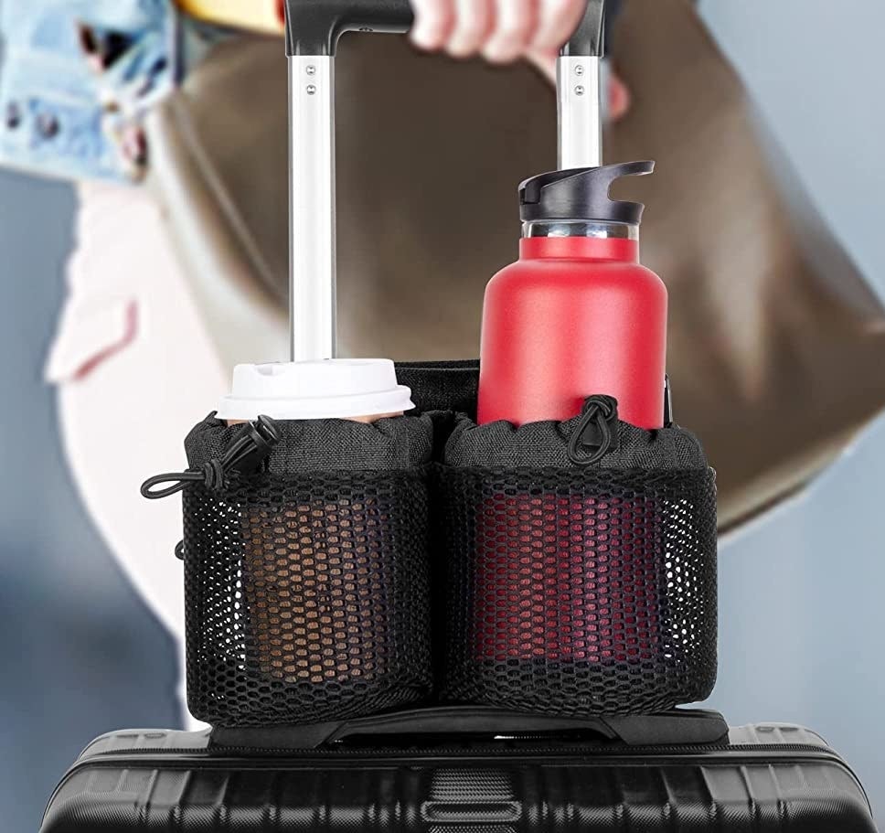person holding a suitcase handle with the caddy and two drinks in it