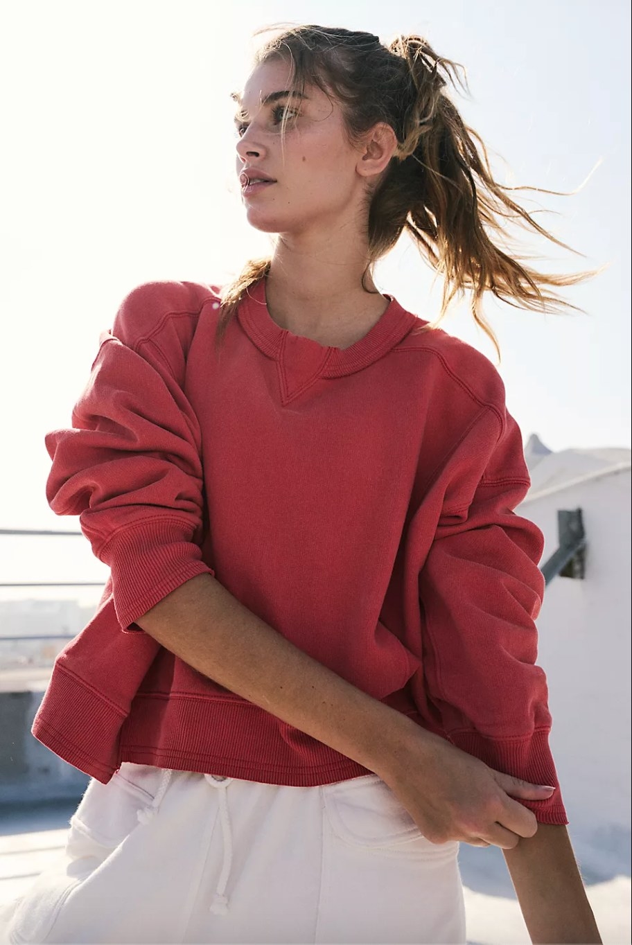 a model wearing the read sweatshirt and white pants
