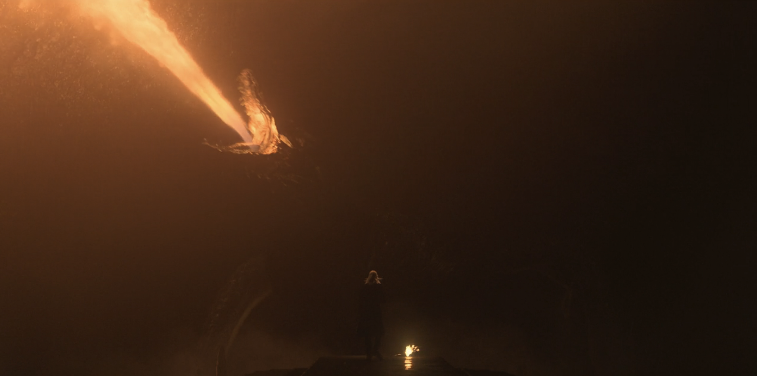 Daemon standing in the dark in front of a huge dragon that is breathing fire