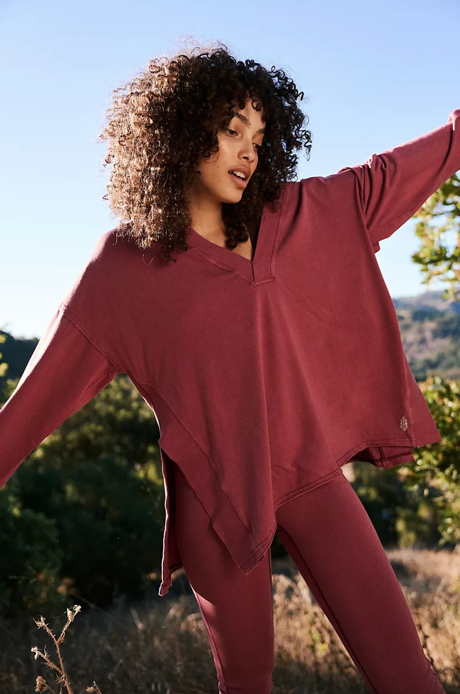 a model outdoors wearing the dark red long sleeved top and pants set