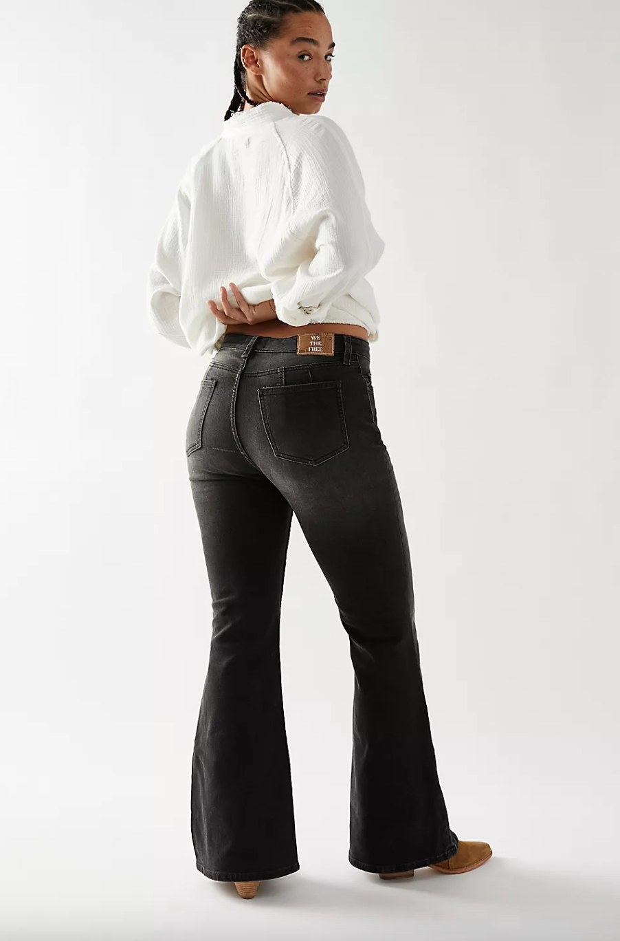 a model wearing the black flared jeans with a white sweater and brown boots
