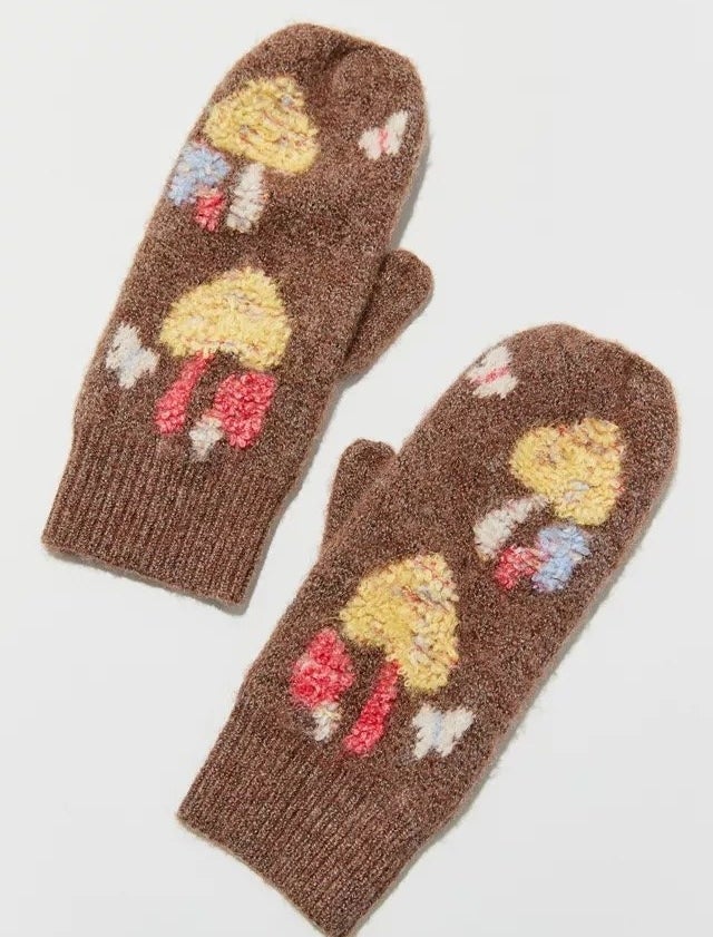 a pair of knitted mittens with mushrooms and butterflies on them