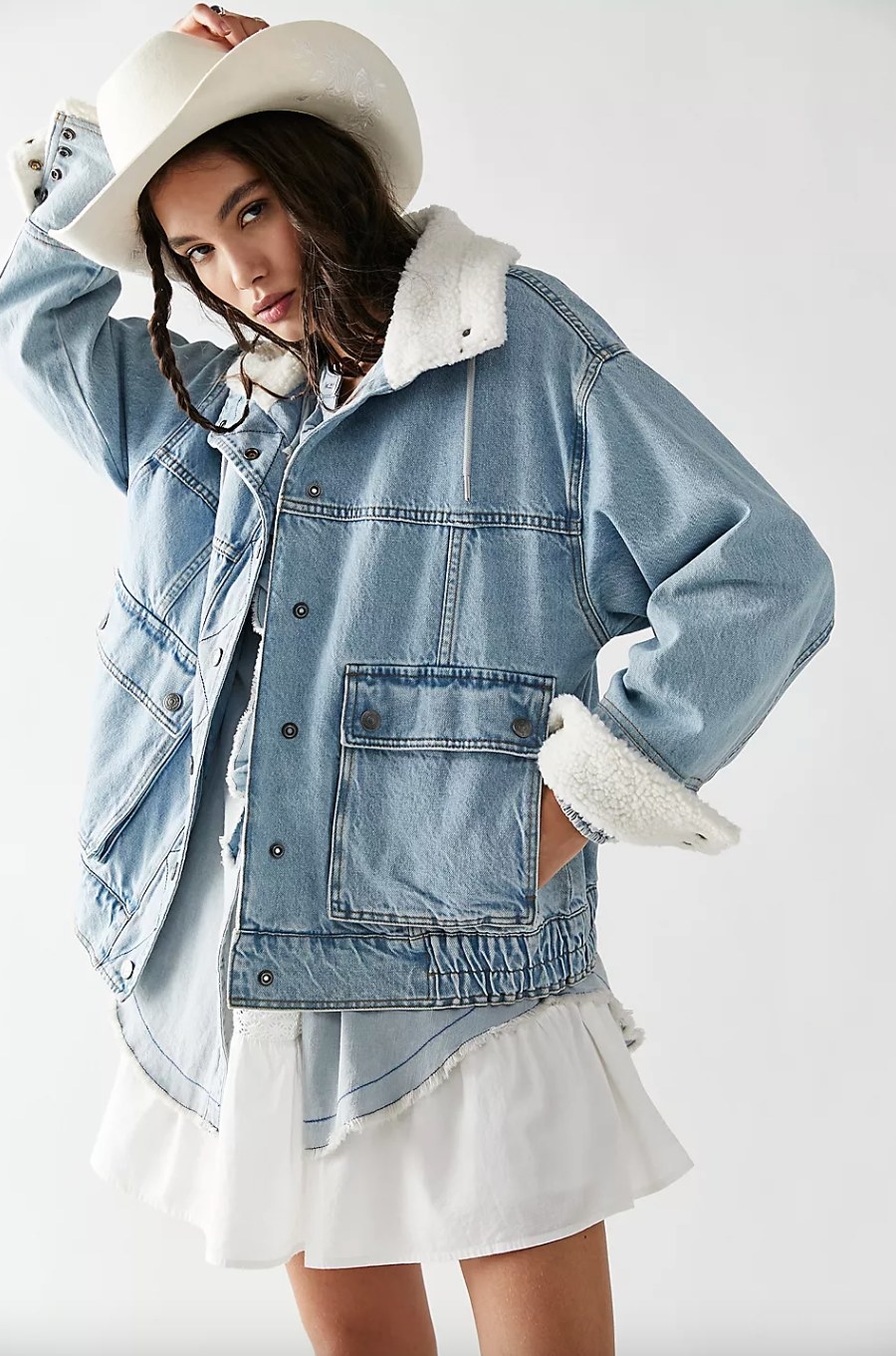 a model wearing the light denim jacket with a white dress and white cowboy hat