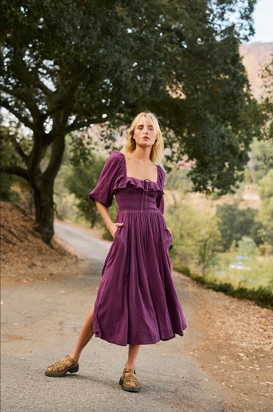 a model outdoors wearing the dark purple dress with puff sleeves