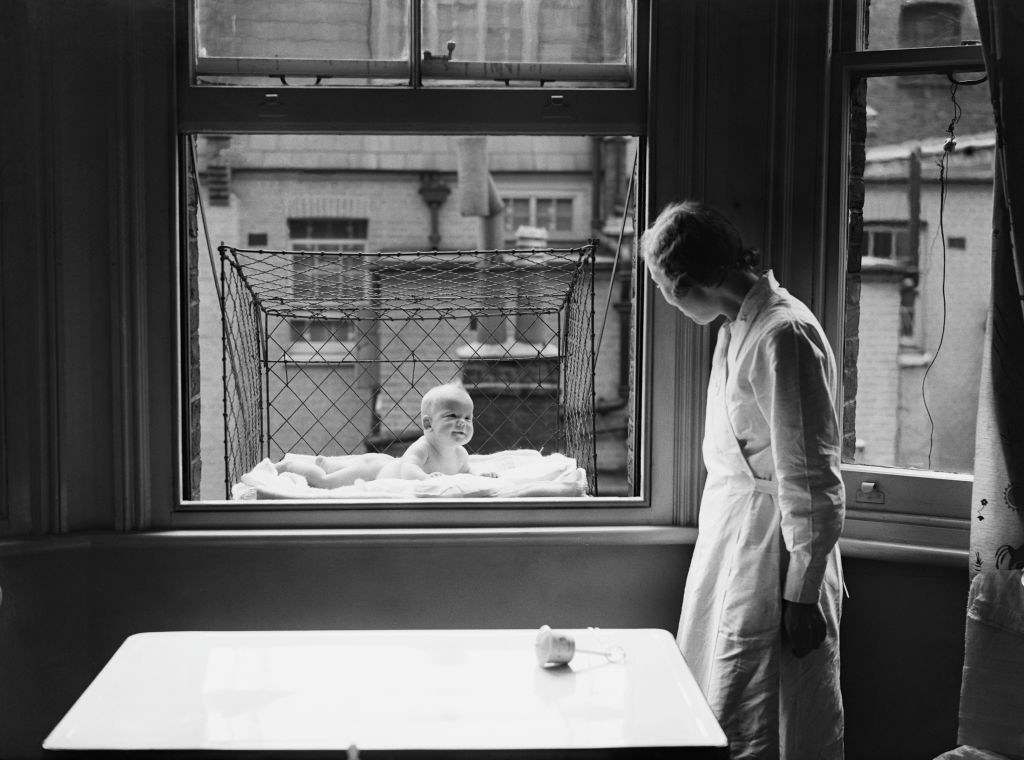 vintage photo of a baby in a window cage from the 1930s