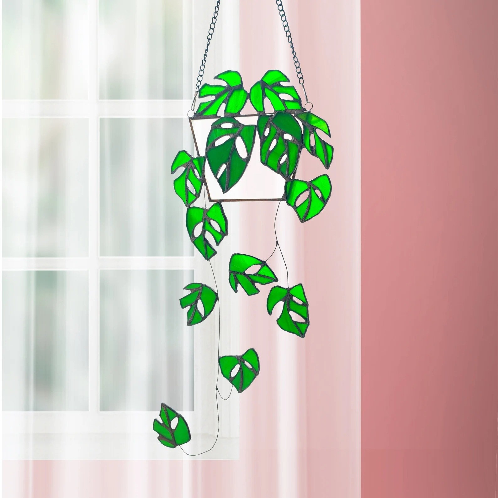 A piece of green stained glass art in the shape of a plant is shown