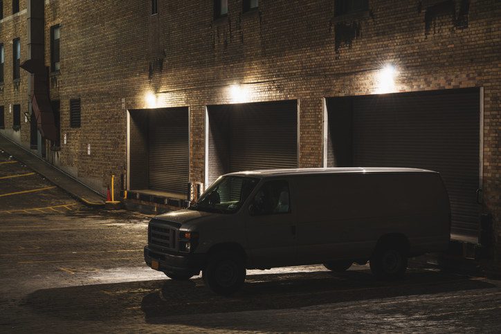 A cargo van is parked in a dark loading dock.