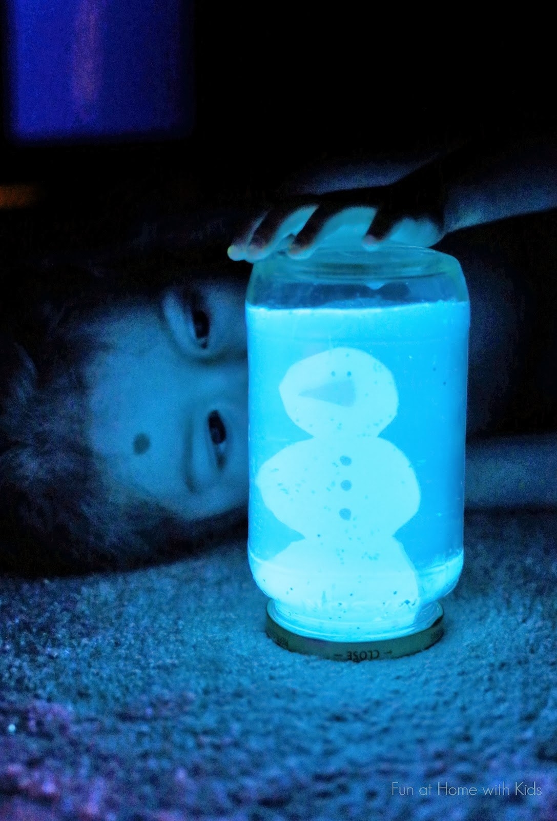 kid holding DIY glowing/light-up blue snow globe