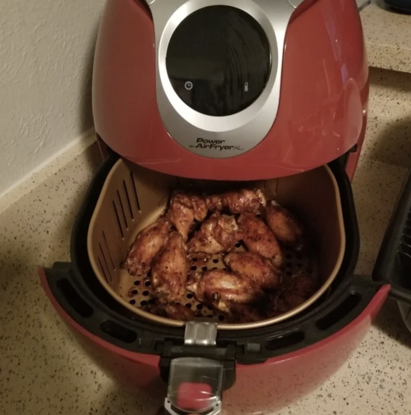 Reviewer&#x27;s photo of the red air fryer pen to show chicken wings in the basket
