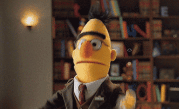 gif of sesame street puppet in a posh outfit looking frustrated in a library