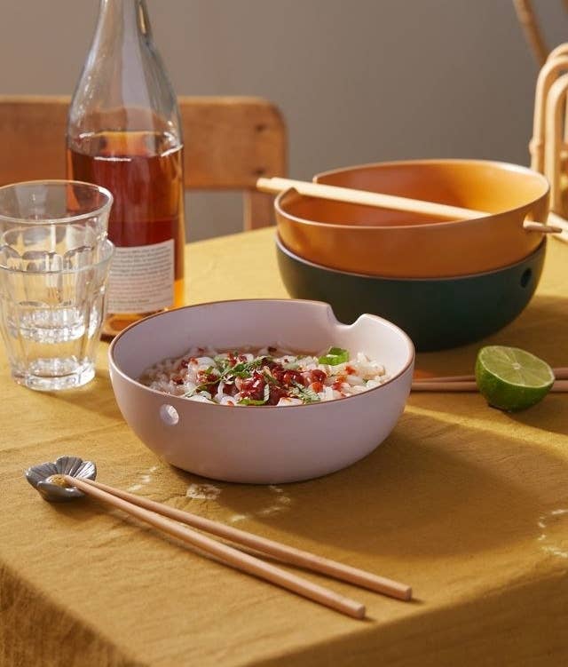 a noodle bowl on a table next to chop sticks and glassware