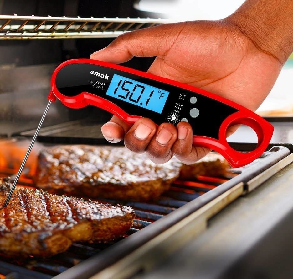 a person using a thermometer to check the status of meat on bbq