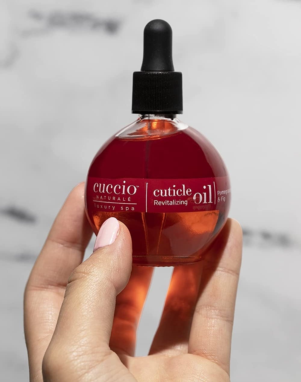 A person holding the bottle of cuticle oil