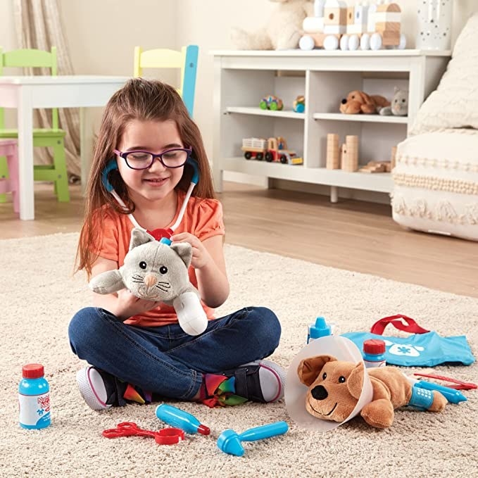 a kid playing with the vet set on a carpet