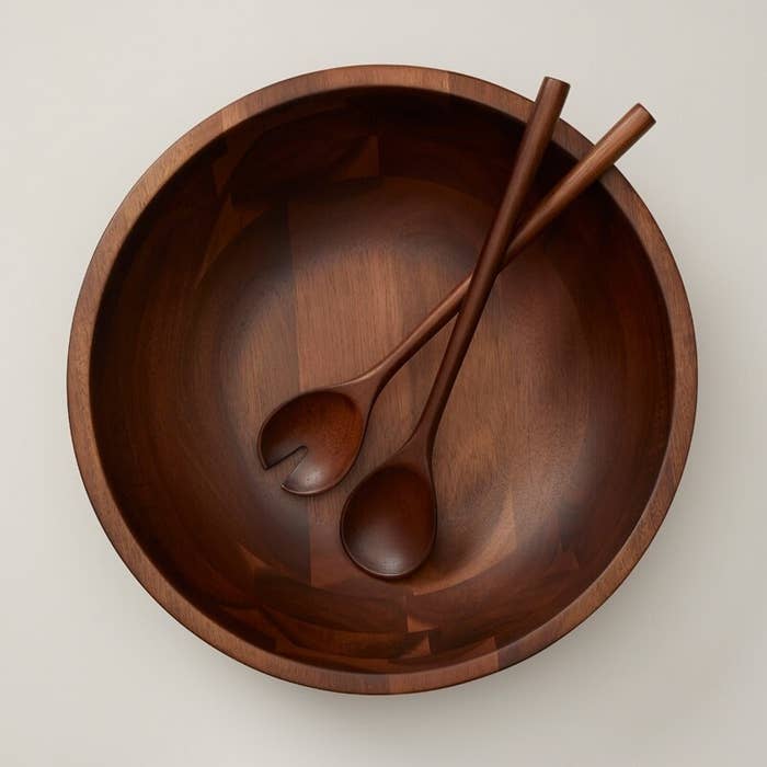 a pair of serving utensils in a large wood bowl