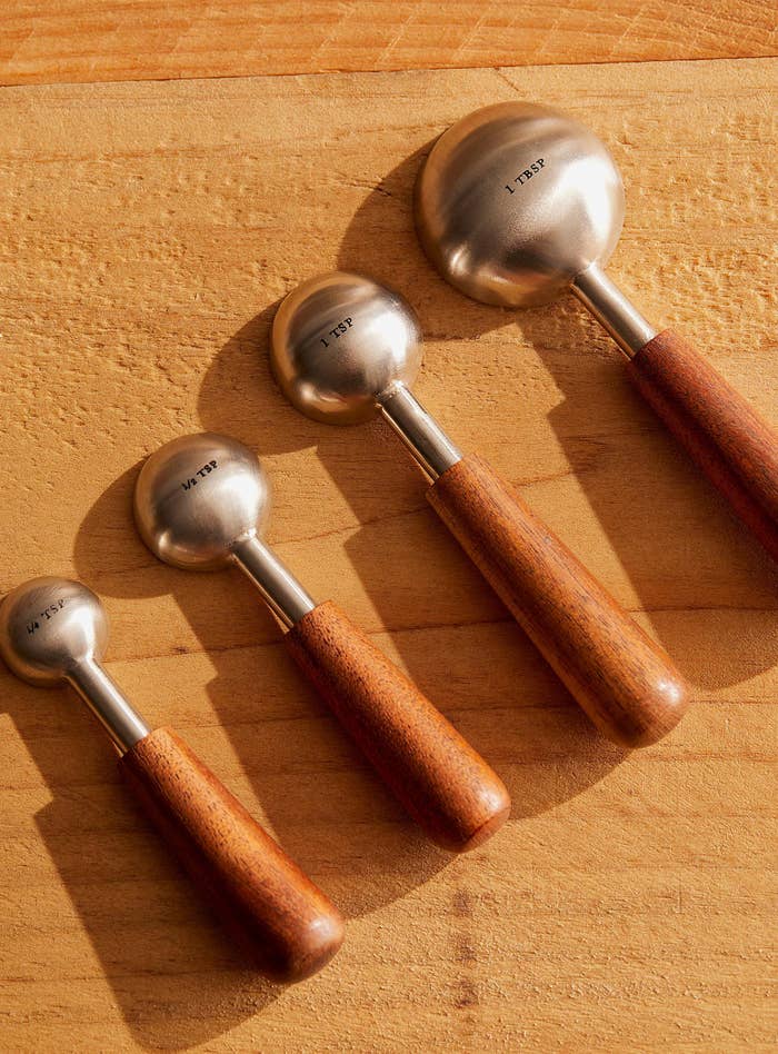 four wood handled measuring spoons on a wood surface