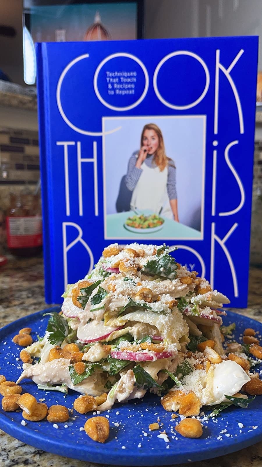 a reviewer&#x27;s caesar salad in front of a copy of molly baz&#x27;s cook book
