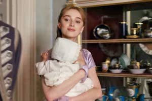 Daphne from Bridgerton holding her baby and smiling softly