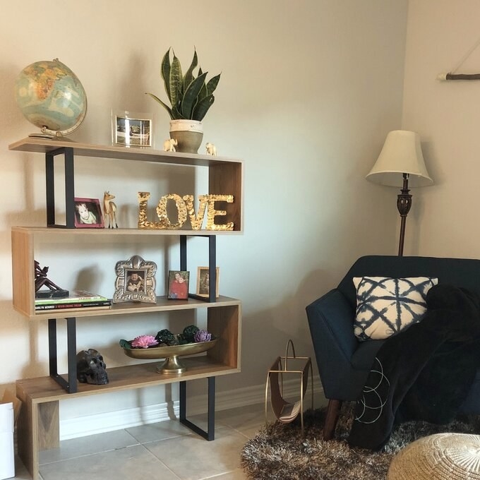 Wooden geometric shelf in living room with decorative items on it