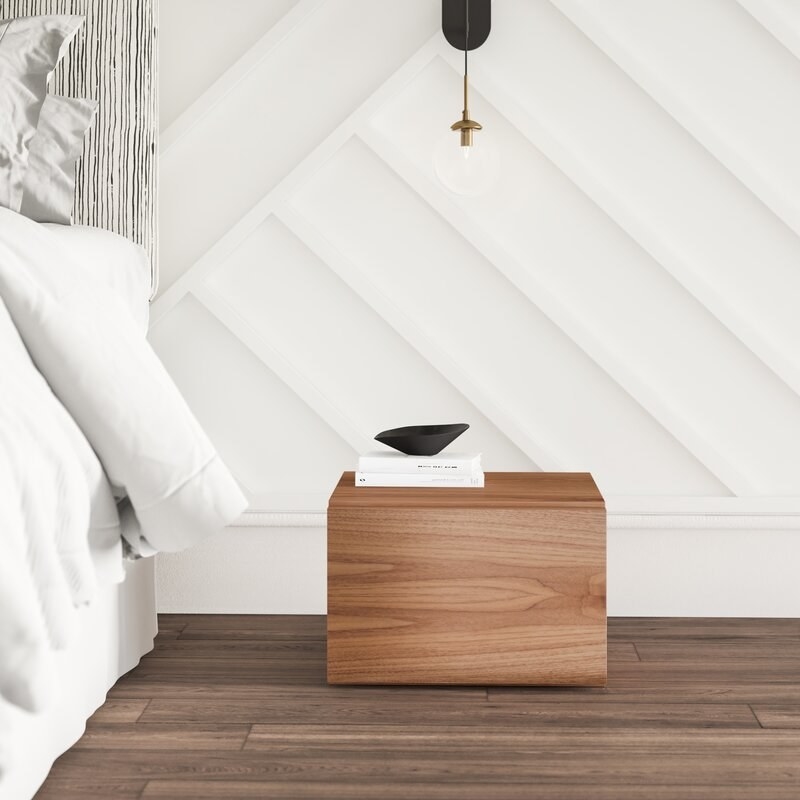 Wooden cube night stand on floor next to bed